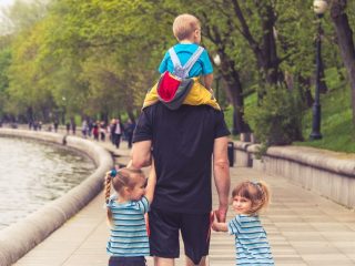 the father walks with three kids in the park